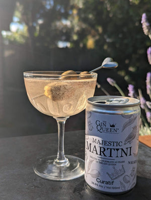 Cocktail glass with martini in it with three olives on heart shaped stick and a can of Majestic Martini to the side