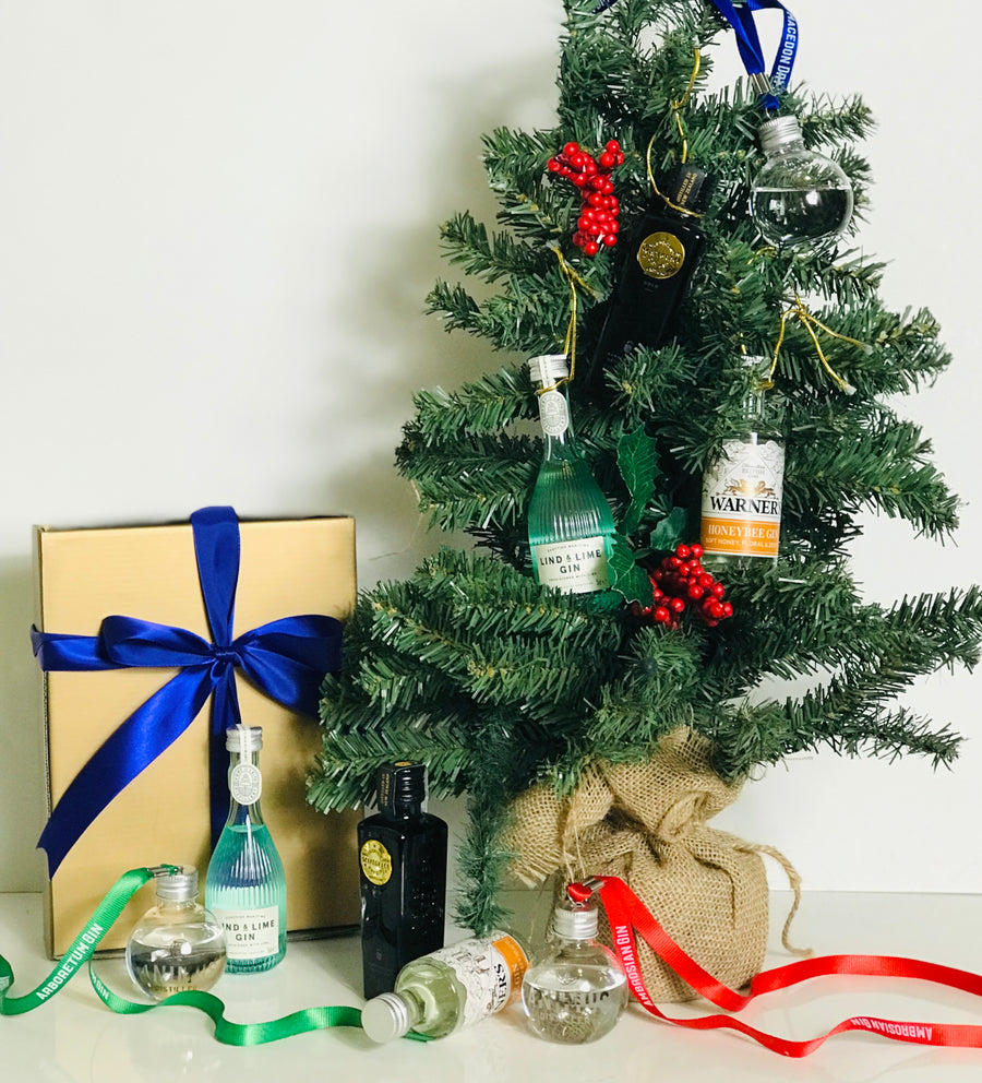 Mini gin bottles hanging on Christmas tree with baubles on foot of tree