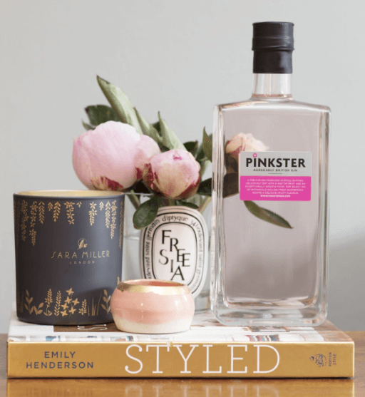 Pinkster Gin on top of Styled book with peony and candle next to it