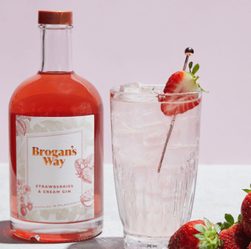 Strawberries & Cream gin bottle next to glass filled with tonic garnished with strawberry