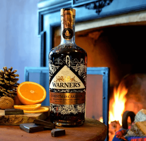 Warner's Christmas Cake gin in front of fire with orange slice and chocolate